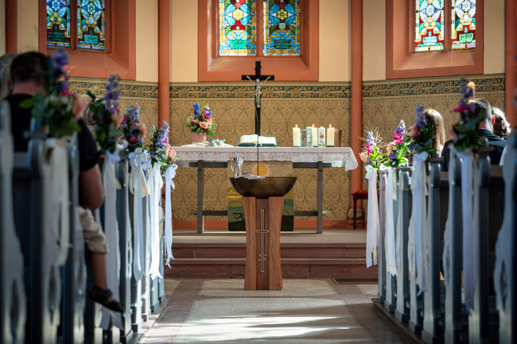 Kirche während einer Tauffeier mit Gästen und Blumenschmuck an den Bänken