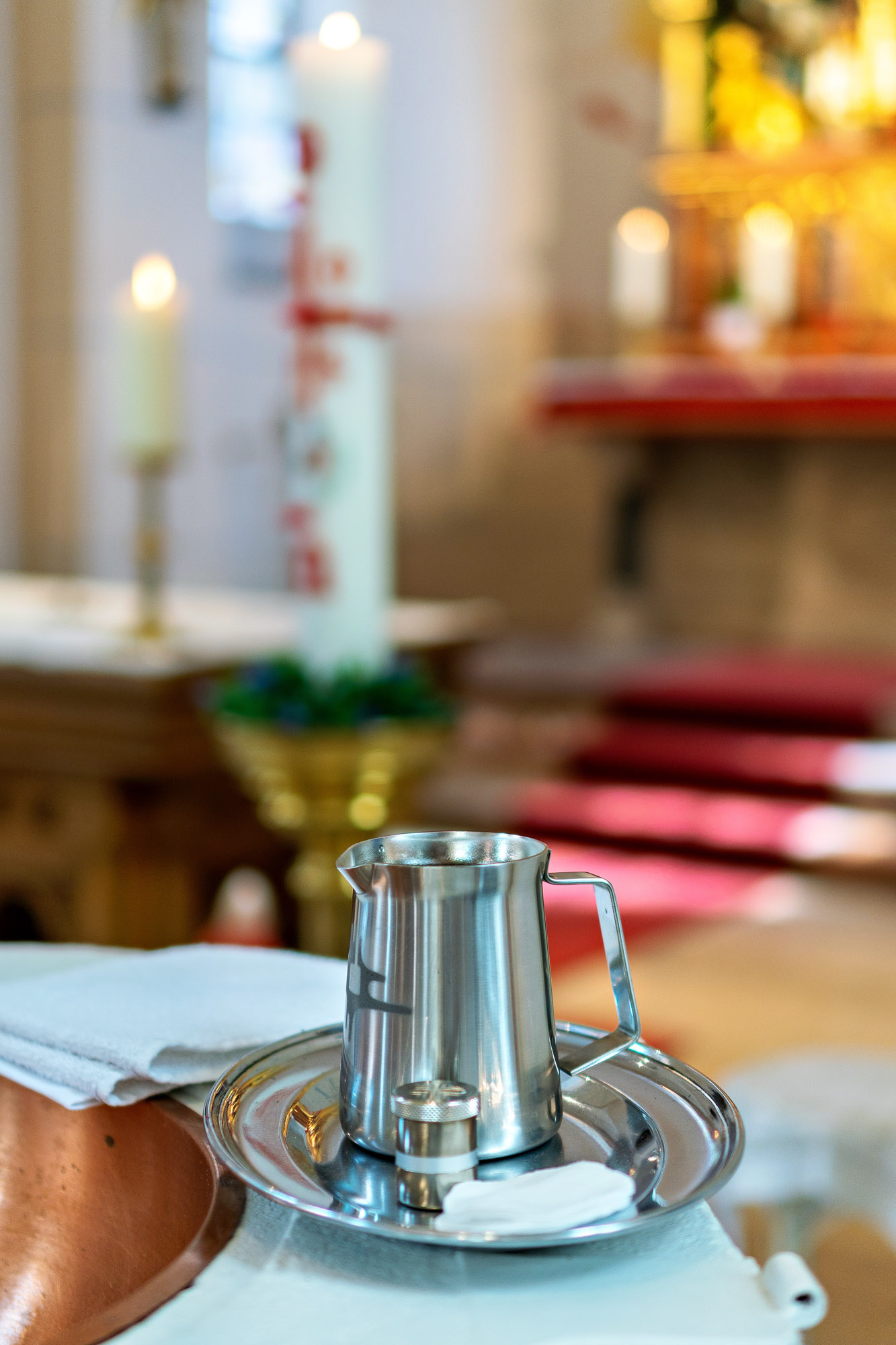 Taufbecken in Nahaufnahme mit Wasserkrug und Kerze in Rodenbach