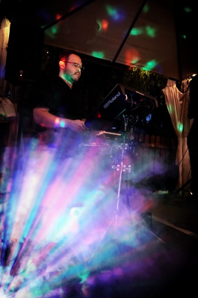 Drummer steht im bunten Lichtnebel w&auml;hrend eines Sommerkonzerts