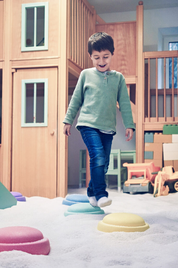 Junge l&auml;uft barfu&szlig; &uuml;ber bunte H&uuml;gel im Salzspielplatz