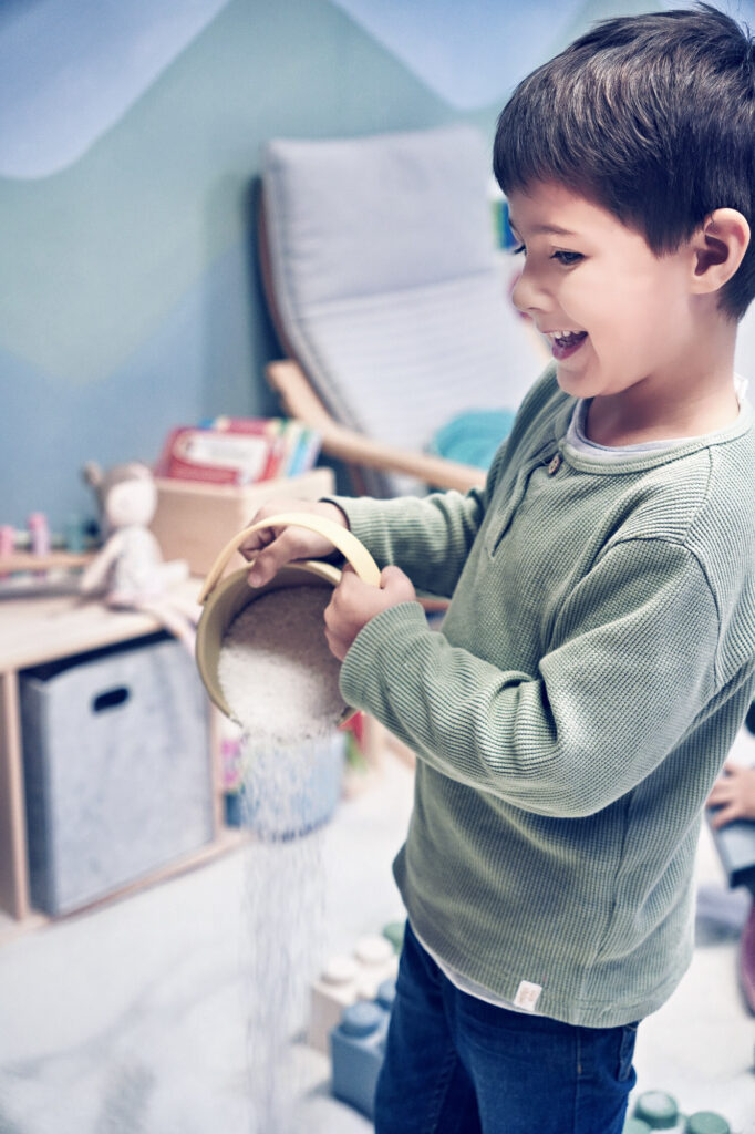 Kind sch&uuml;ttet lachend Salz aus einem Eimer