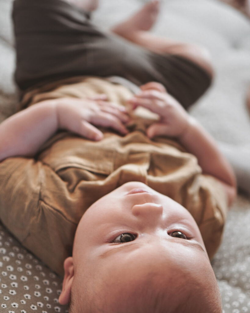 Baby liegt entspannt auf Bett &ndash; authentisches Newbornshooting im Main-Kinzig-Kreis