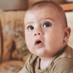 Baby mit wachem Blick auf Sofa &ndash; Newbornfotografie Rhein-Main-Gebiet