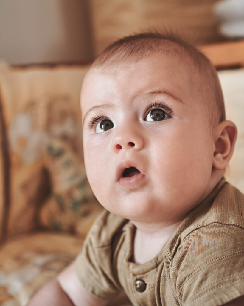 Baby mit wachem Blick auf Sofa &ndash; Newbornfotografie Rhein-Main-Gebiet