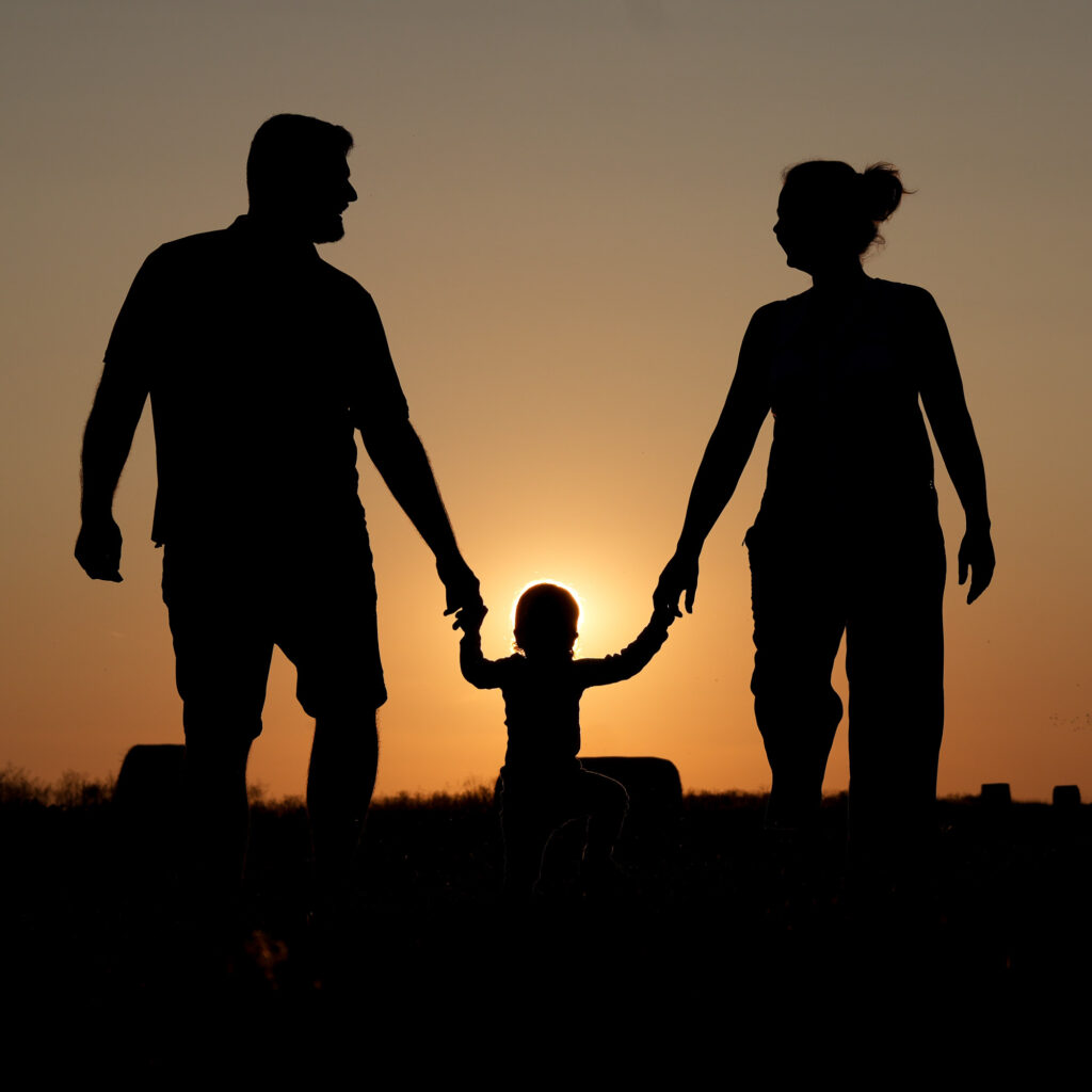 Silhouetten von Mutter, Vater und Kind vor untergehender Sonne beim Familienshooting im Rhein-Main-Gebiet