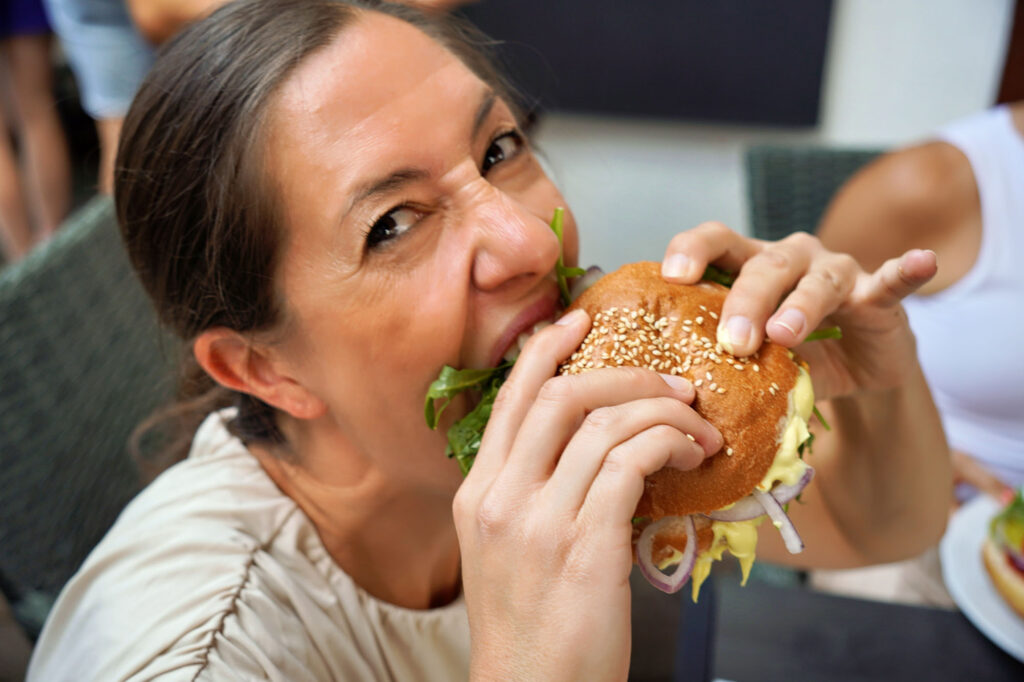 Frau nimmt herzhaften Biss von ihrem Burger bei Sommerfest in Gelnhausen &ndash; lebendige Eventszene.