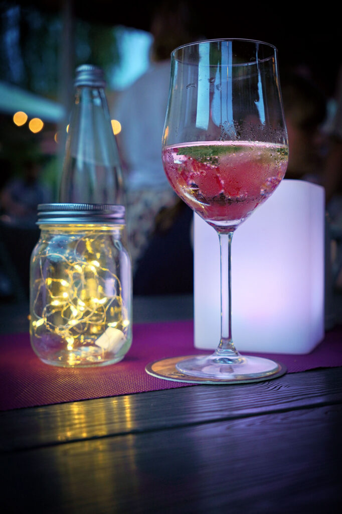 Weinglas mit Beeren neben beleuchtetem Dekoglas bei Sommernacht im Rhein-Main-Gebiet – festlich & gemütlich.