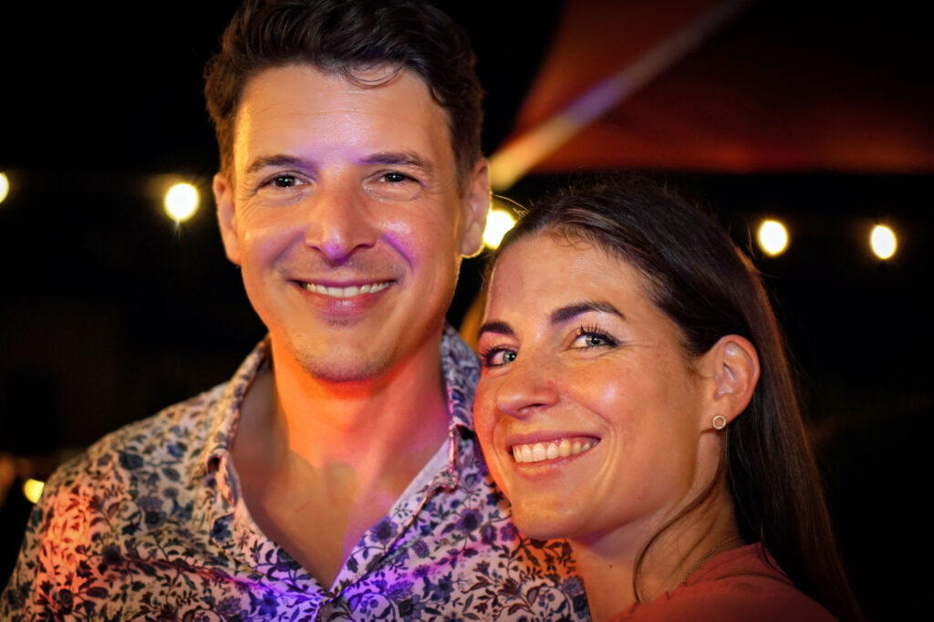 Fröhliches Paar lächelt gemeinsam in die Kamera bei Gartenparty im Main-Kinzig-Kreis – lebendiges Porträt.