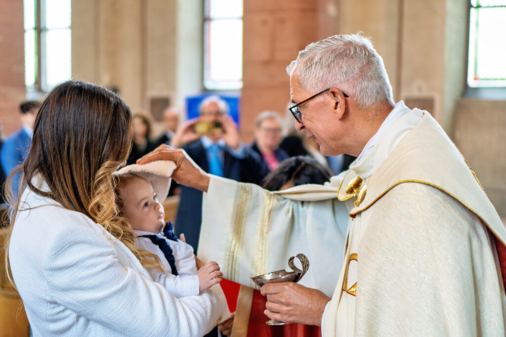 Priester segnet Baby bei Tauffeier in Hanauer Kirche