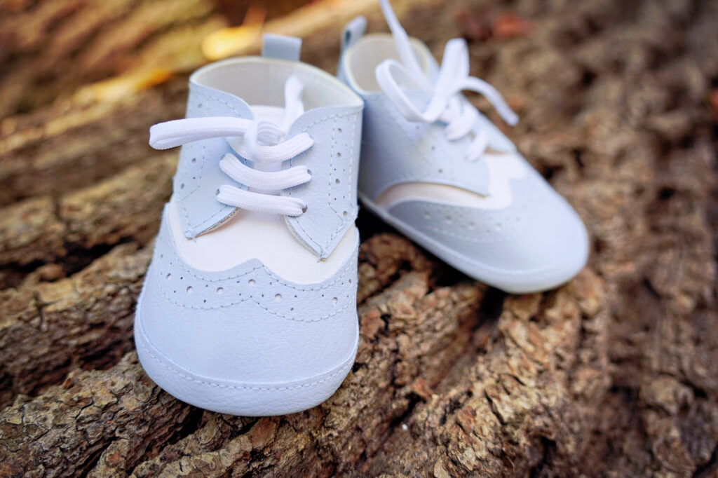Kleine Babyschuhe auf Baumrinde als symbolisches Taufmotiv