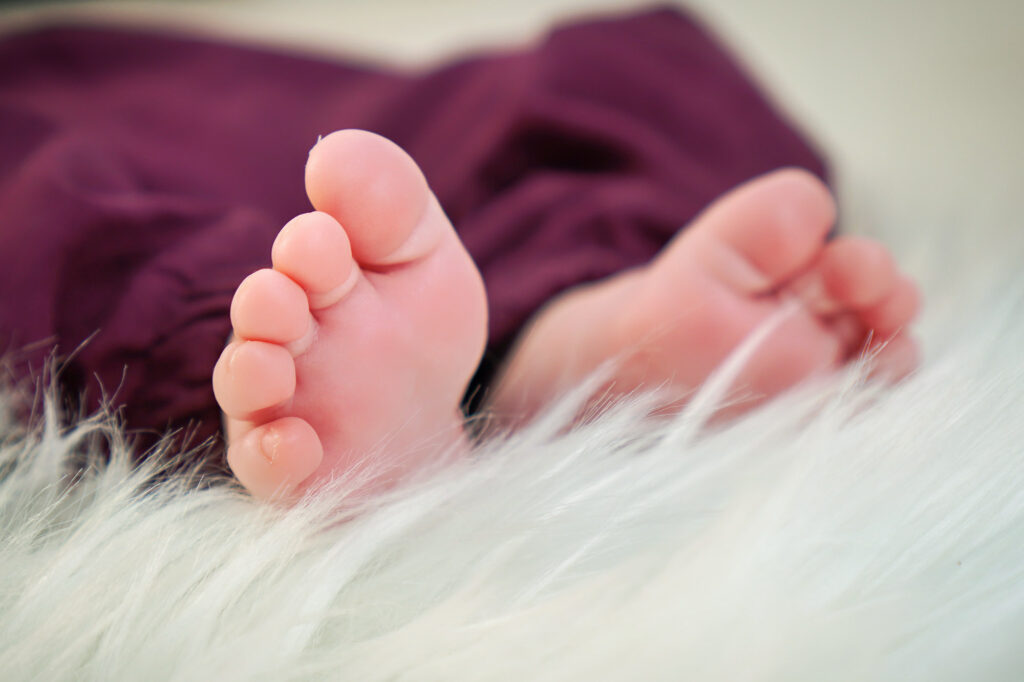 Detailaufnahme von Babyfüßen auf weißem Fell – Newbornshooting in Gelnhausen