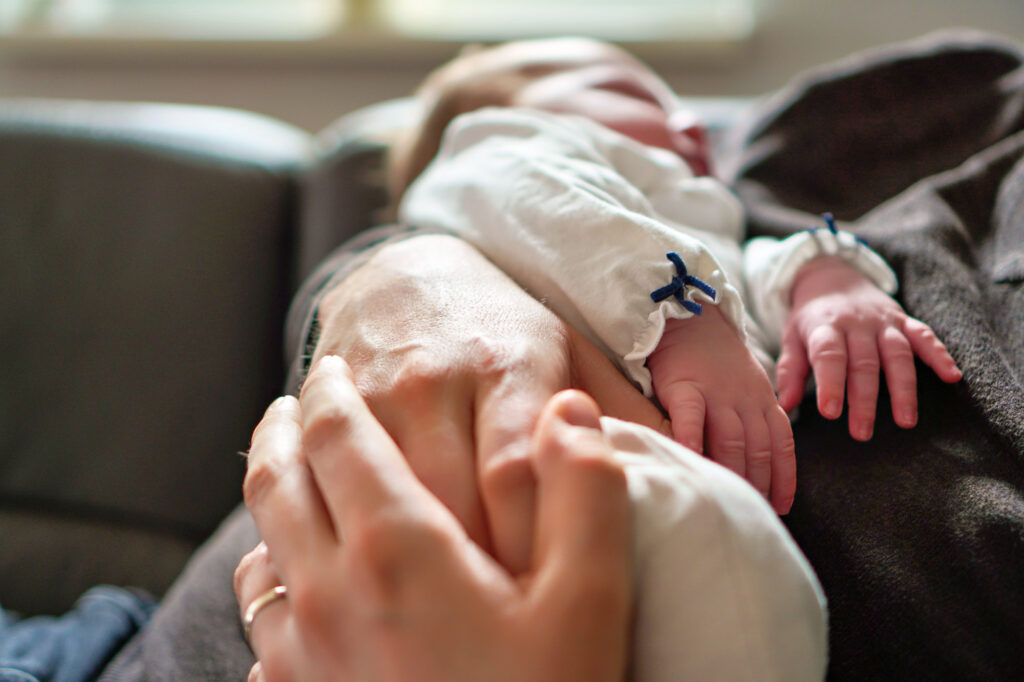Eltern halten die Hand ihres Babys &ndash; inniger Moment beim Newbornshooting in Bruchk&ouml;bel