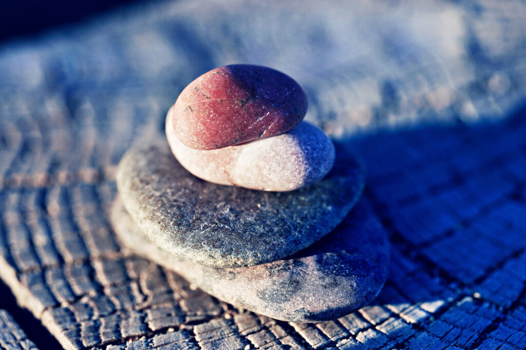 Gestapelte Natursteine auf einem Baumstumpf im Licht