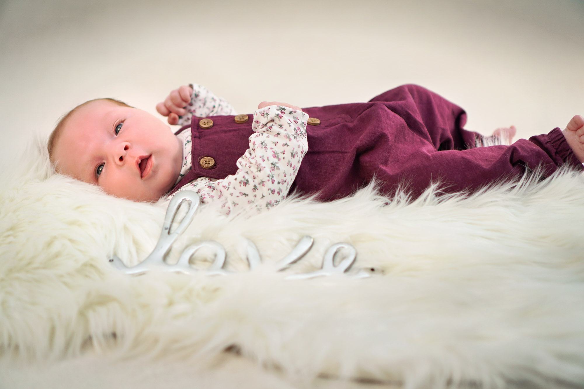 Newborn liegt auf weißem Fell mit Love-Schriftzug – emotionales Homeshooting im Rhein-Main-Gebiet