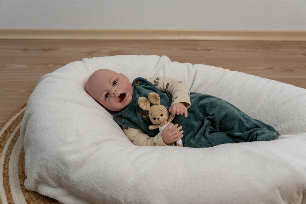 Babypuppe liegt auf dem Boden mit Hasen in der Hand und fotografiert mit 24 mm