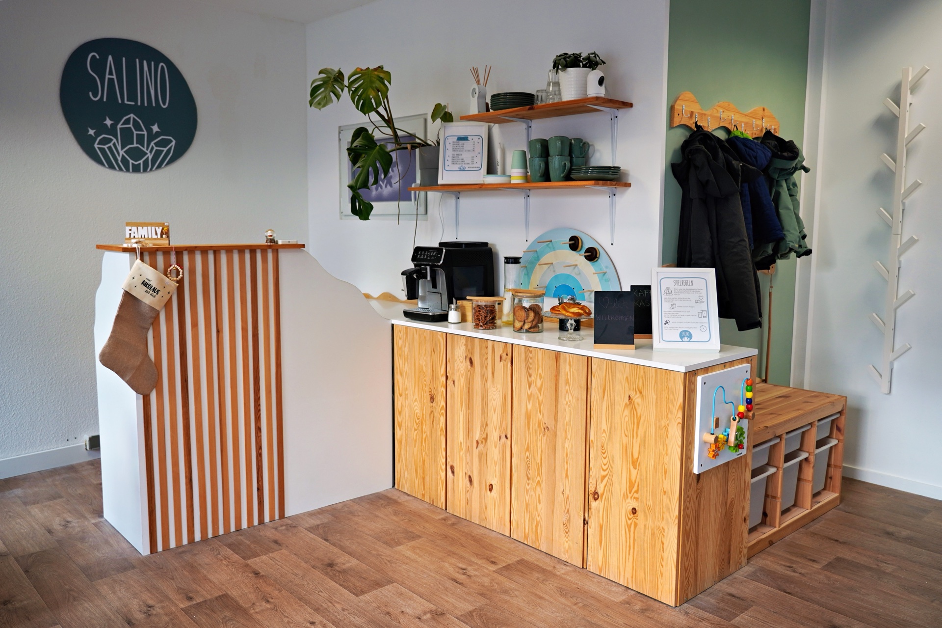 Eingangsbereich des Salino Gelnhausen mit gem&uuml;tlicher Holztheke, Snacks f&uuml;r Eltern und Spielzeug f&uuml;r Kinder