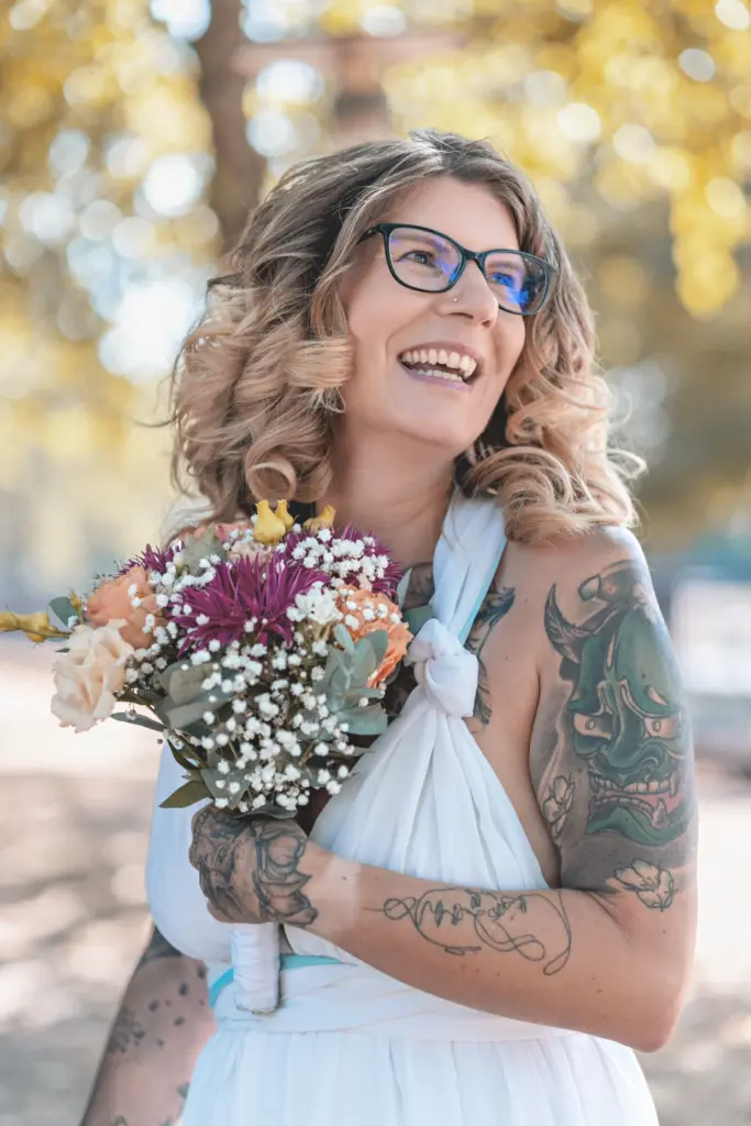 Lachende Braut mit buntem Blumenstrau&szlig; im Boho-Stil