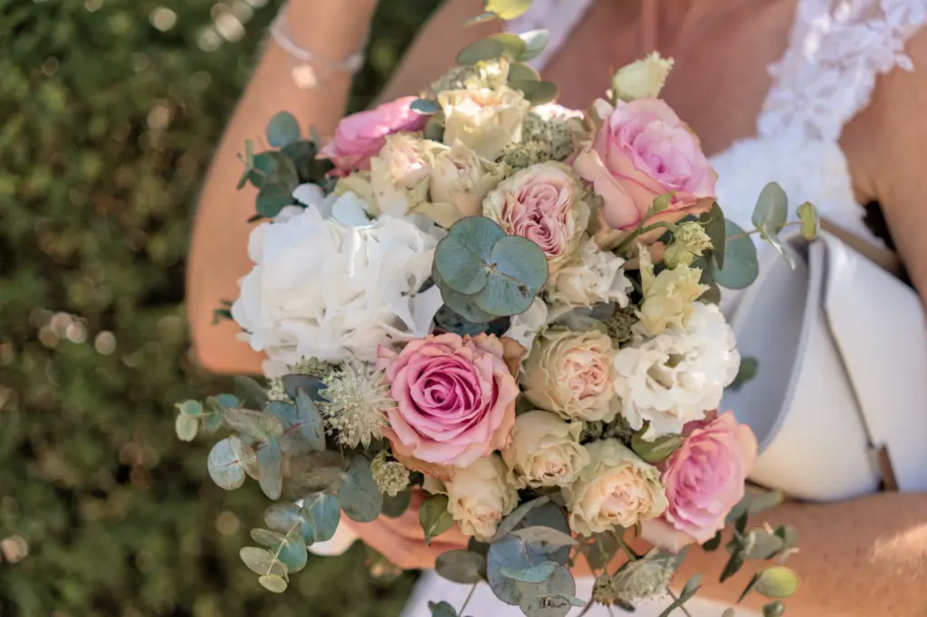 Brautstrau&szlig; aus rosa und wei&szlig;en Rosen mit Eukalyptus, gehalten von der Braut im wei&szlig;en Kleid