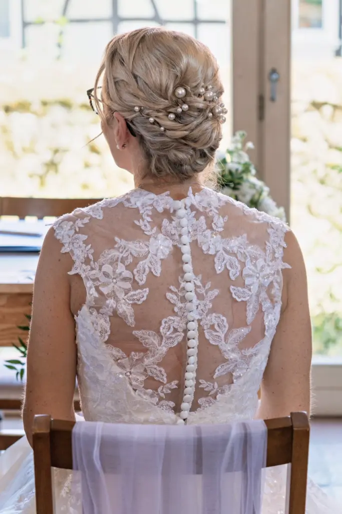 Braut von hinten bei der Trauung, Kleid mit filigranem Spitzenr&uuml;cken und Knopfleiste, Hochsteckfrisur