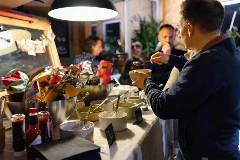 G&auml;ste bedienen sich an einer Buffetstation mit Saucen und Schalen, im Vordergrund probiert ein Mann